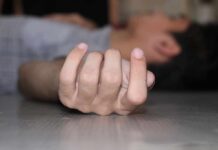 Close-up of a hand on the floor with person lying in background