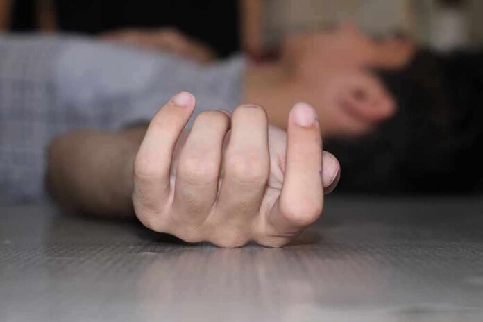 Close-up of a hand on the floor with person lying in background