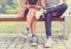 Two people sitting on a park bench using mobile devices