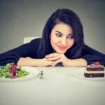 Mind-Taste Trick Supercharges Snack Urges Woman choosing between salad and chocolate cake