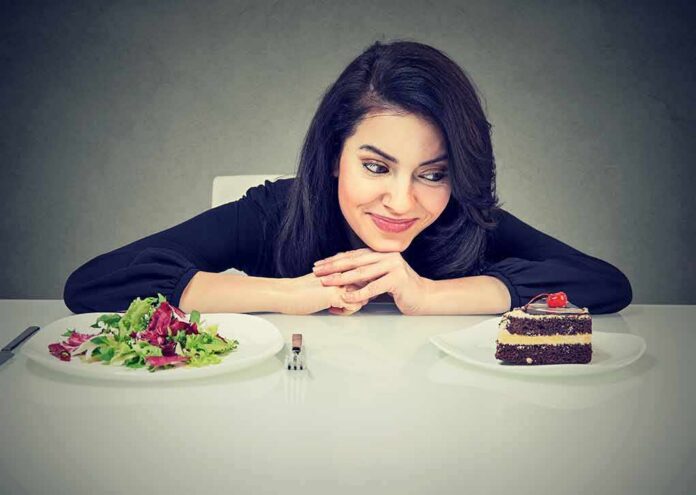 Woman choosing between salad and chocolate cake