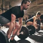 Two people performing deadlifts in a gym