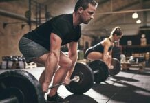 Two people performing deadlifts in a gym